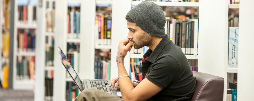 Student studying in the library looking at a laptop